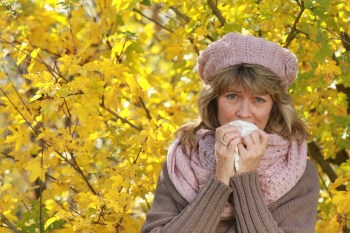 Mature woman blowing her nose in the fall