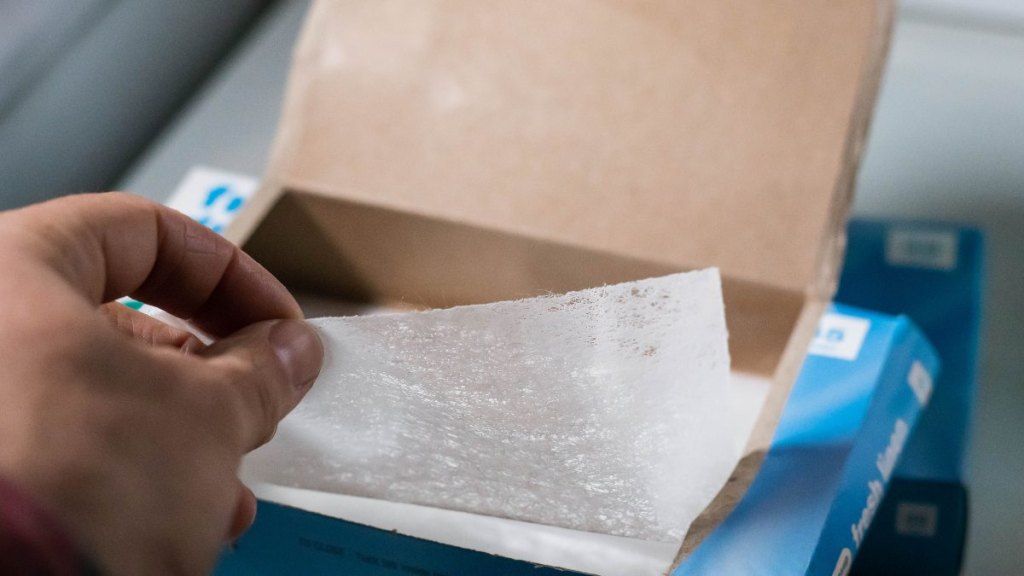 hand pulling a dryer sheet out of a box
