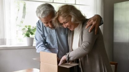 mature couple smiling as they open an anniversary gift