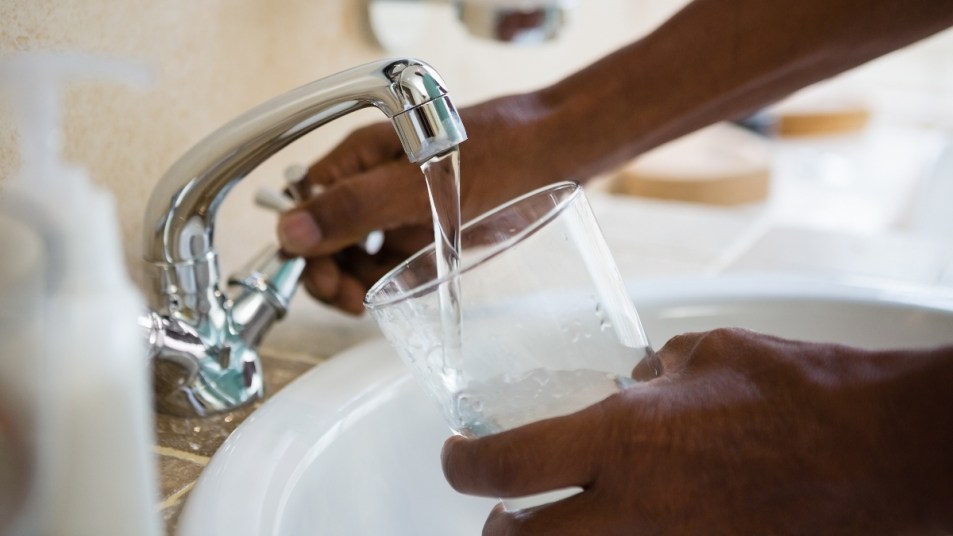 mature woman filling glass with tap water from faucet