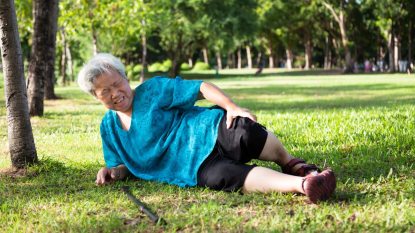 mature woman who suffered a fall outside in a park, holding her knee