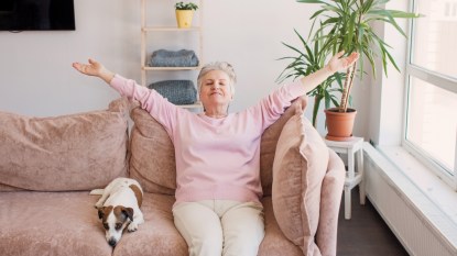 Relaxed satisfied older woman sitting leaning back on couch in air conditioner room, happy peaceful mature female with outstretched arms resting on sofa at home, enjoying fresh air, breathing