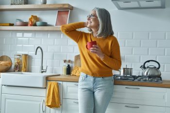happy senior woman in kitchen with coffee