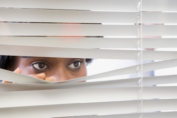 Woman peering out through window blinds