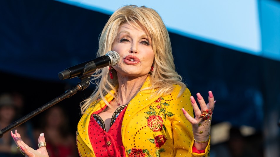Dolly Parton in yellow rose jacket singing in 2019