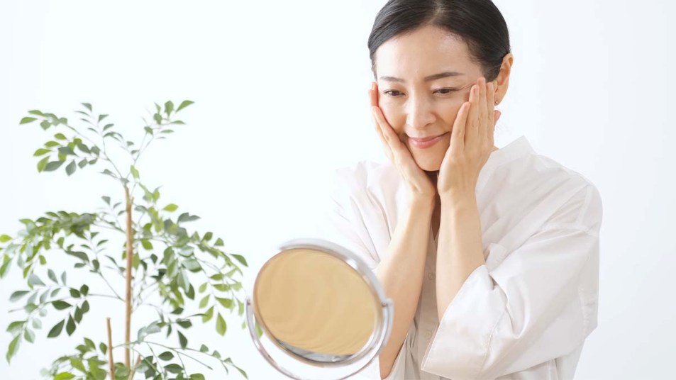 Woman touching her face and looking in the mirror