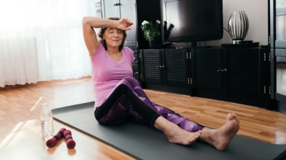 mature woman sweating on yoga mat after an intense workout, staying active