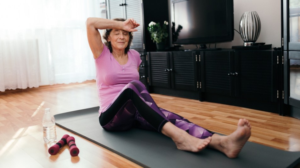 mature woman sweating on yoga mat after an intense workout, staying active