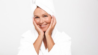 Image of feminine adult woman wearing bathrobe and towel over her head smiling isolated over white background