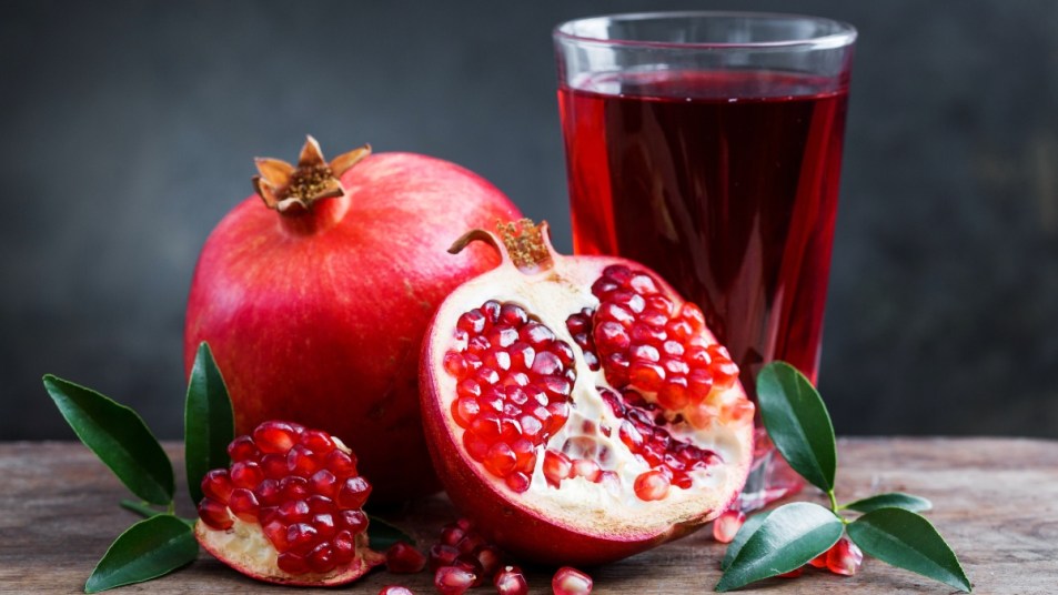Pomegranate juice with pomegranate on a wooden board on a dark background