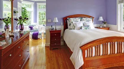 Bedroom interior with purple walls, brown furniture and hardwood floor