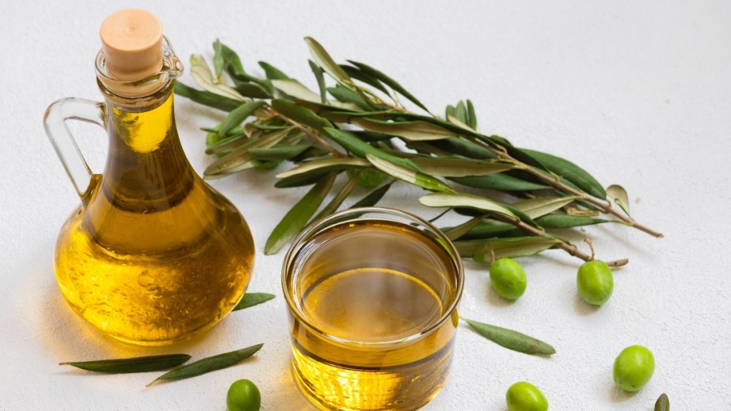 Bottles of olive oil next to fresh olives and and olive branch