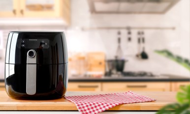 An electric Air Fryer on table with blurred kitchen background