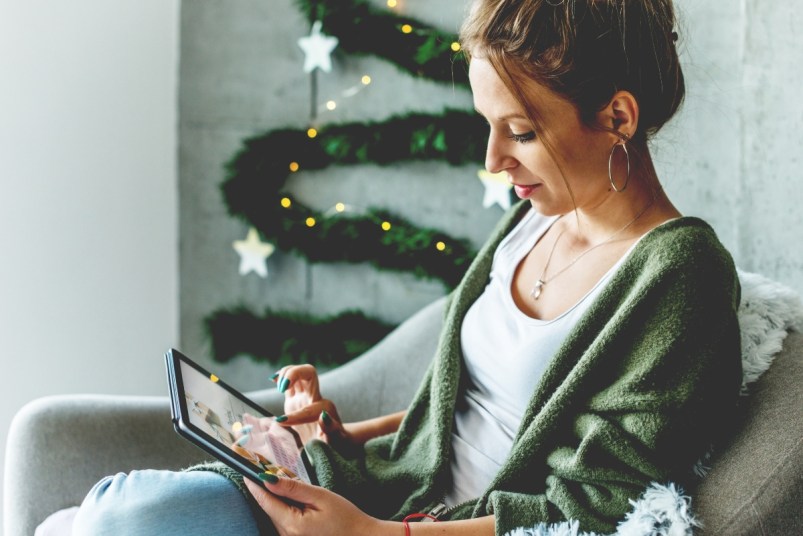 Woman shopping for holiday deals on the couch using her tablet