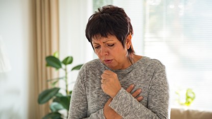 mature woman with short brown hair and seasonal upper respiratory issues, coughing