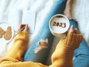 2023 coffee cup held by woman writing down her New Year's resolutions