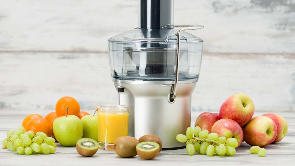Modern electric juicer with various fruits and a glass of freshly made juice