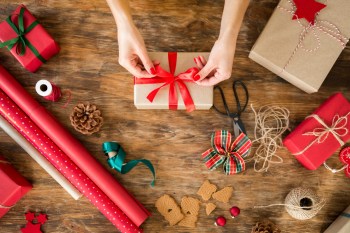 Woman wrapping beautiful christmas gifts on rustic wooden table