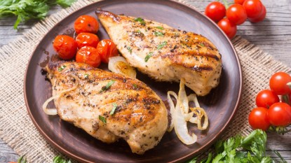 grilled chicken breast on a brown plate with tomatoes