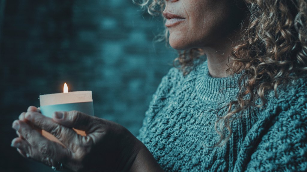woman holds a votive as the remembers a loved one