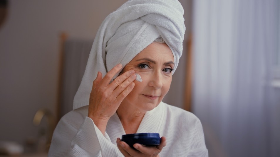 mature woman in white robe applying a thick ointment, one of the slugging products