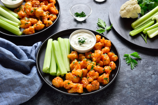 Plates of Buffalo cauliflower with celery and blue cheese dressing