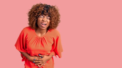 Young african american woman wearing casual clothes with hand on stomach because nausea, painful disease feeling unwell. ache concept.