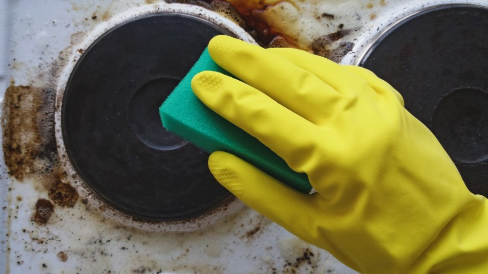 Hand in glove washing messy kitchen stove