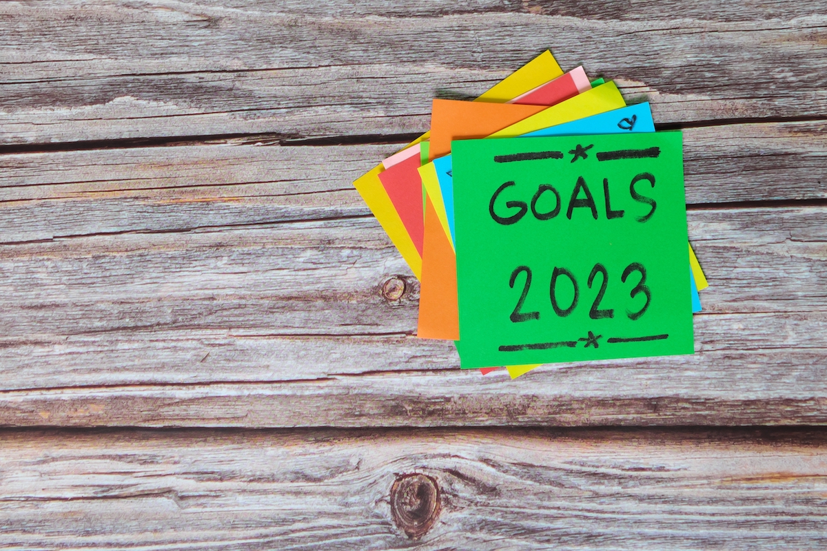 Post-it notes with goals for 2023 on wooden background