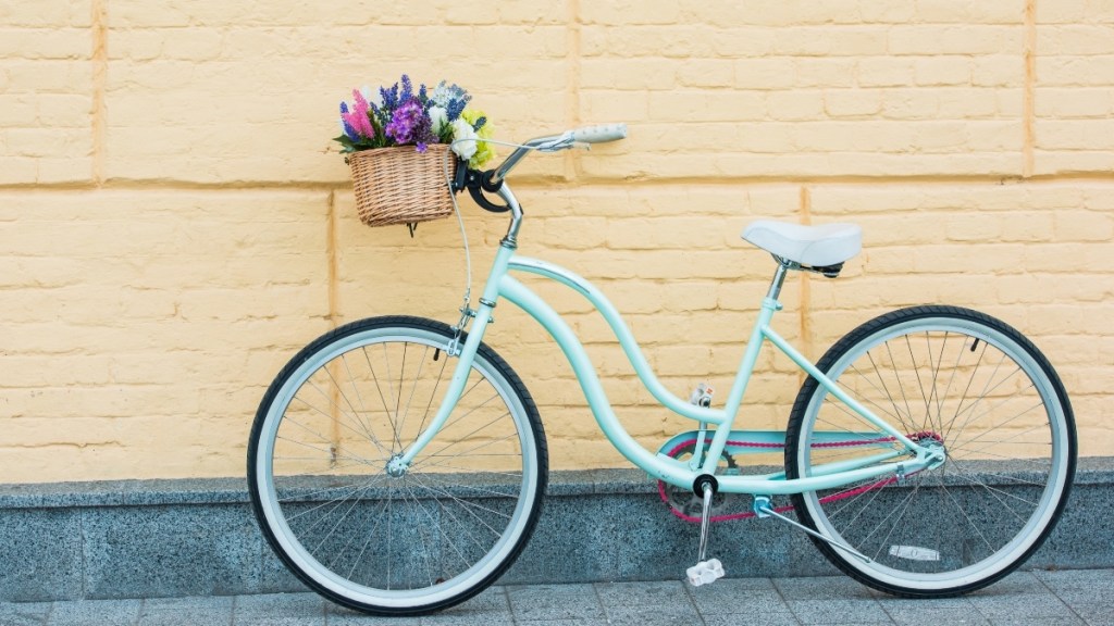 A blue bike against a yellow wall with a basket of flowers