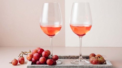 Two glasses of rosé wine and a bunch of red grapes