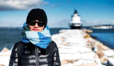 A woman bundled up in scarf and hat on a blue sky winter day