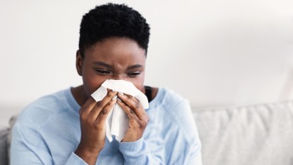 mature woman blowing stuffy nose into tissue