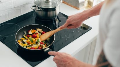 mature woman cooking vegetables on an electric stove