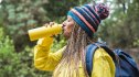 mature woman hiking and drinking water out of a yellow bottle