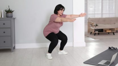 mature woman in a pink shirt doing a glute workout at home