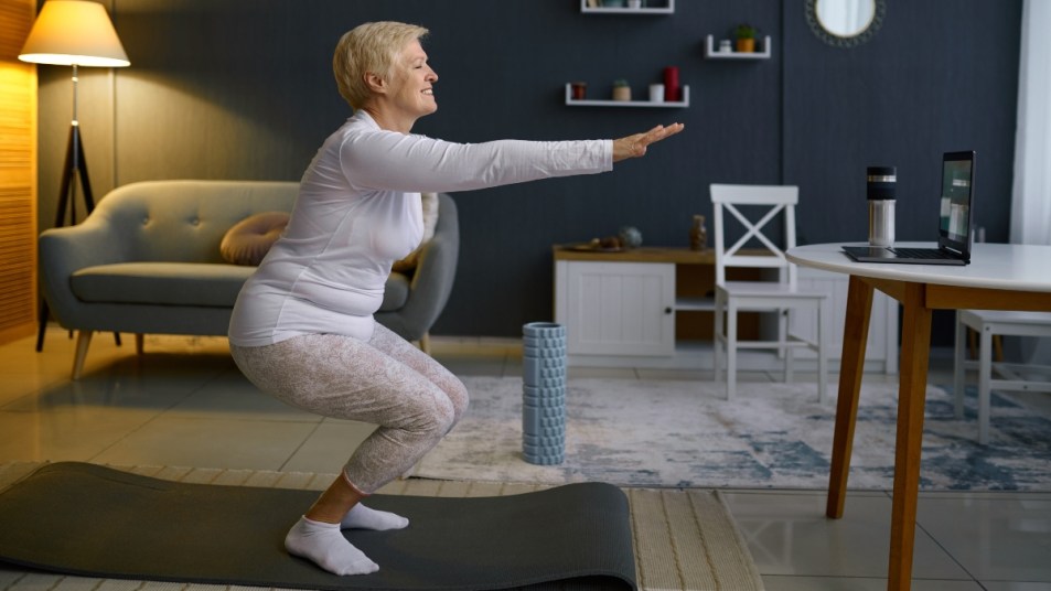 mature woman in white shirt and leggings doing a squat to strengthen her knees