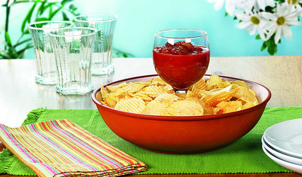 Bowl of chips with wine glass filled with dip in middle