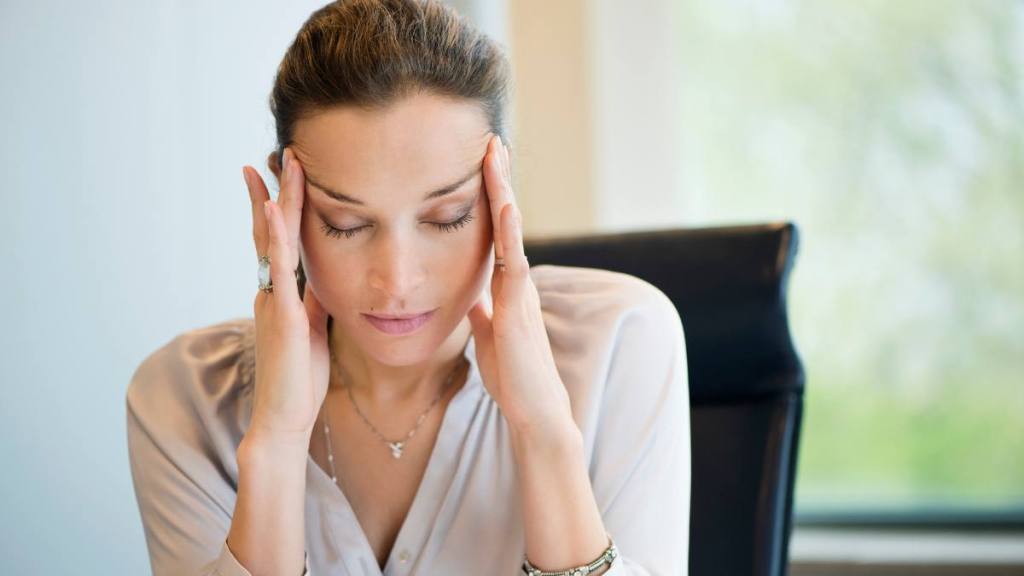 Close-up of a businesswoman suffering from a headache in an office: What does a humidifier do? 
