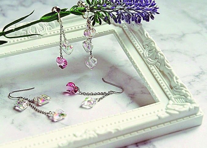 pink heart earrings display on white frame on marble background