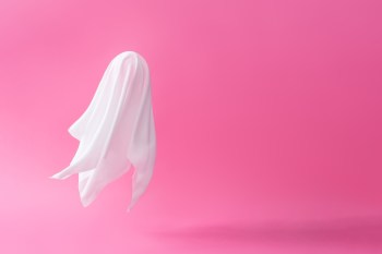 White ghost sheet costume against pastel pink background