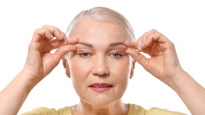 mature woman doing face yoga on her eyes