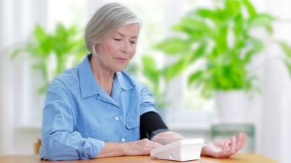 mature woman using a blood pressure cuff at home