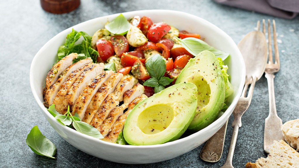 Caprese salad in a bowl with grilled chicken, avocado and tomatoes