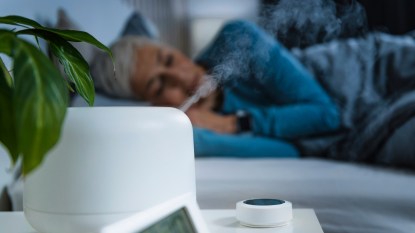 Air Humidifier increasing the humidity in a bedroom for better sleep. Beautiful mature woman sleeping in bed.