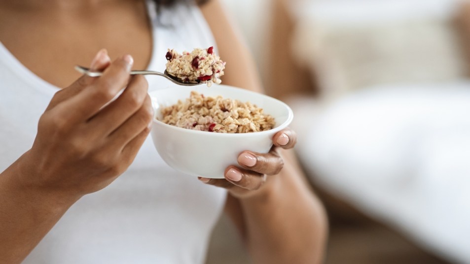 Healthy Meal Concept. Cropped portrait of black woman eating oatmeal with fruits for breakfast, closeup