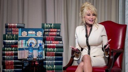 Singer Dolly Parton poses next to stacks of books
