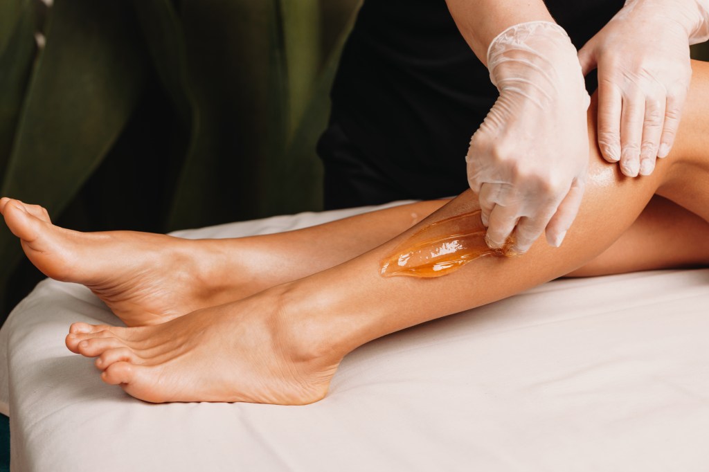 A woman getting sugaring done to her legs at a salon