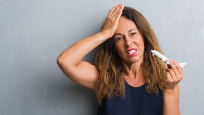 Woman holding a mini airplane while looking stressed