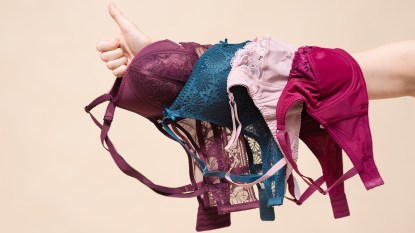Woman with various bras on her arm and a thumbs up gesture